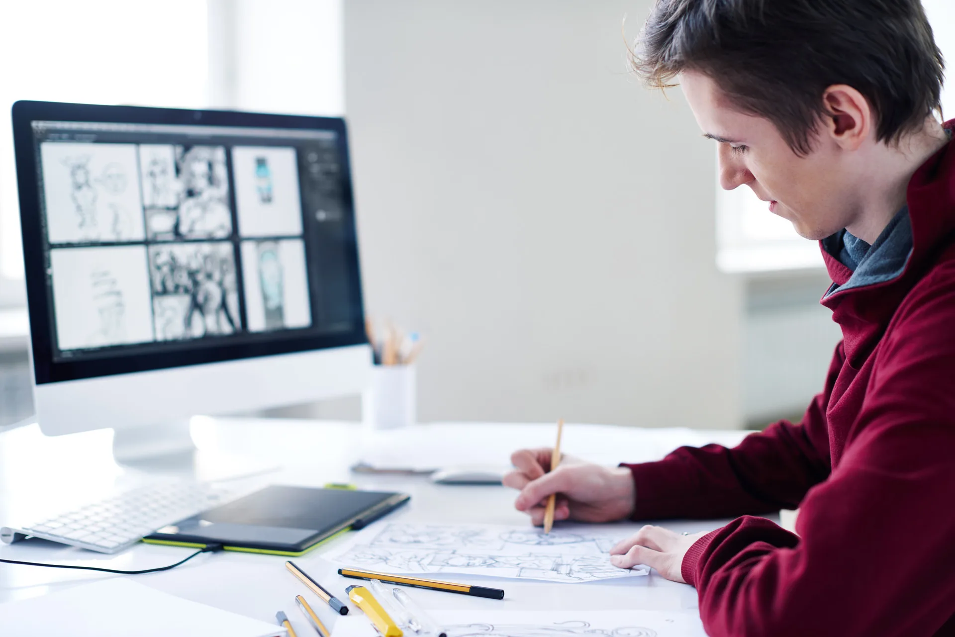 Illustrator sketching at desk with reference materials